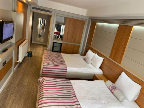 Habitación de hotel con 2 camas y TV de pantalla plana. en May park HOTEL, en Izmir