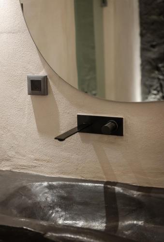 a mirror on a wall next to a sink at One of One - Aether in Oia