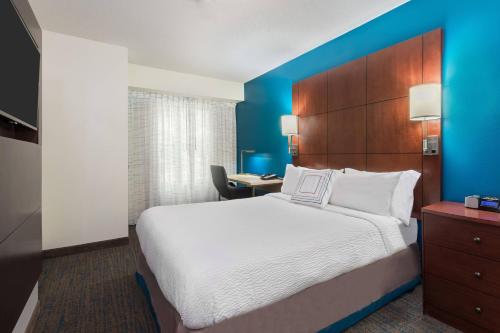 サバンナにあるResidence Inn Savannah Midtownの大きなベッドとデスクが備わるホテルルームです。