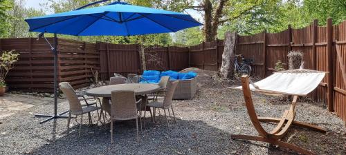 a table and chairs with a blue umbrella in a backyard at The parrot hotel, live in a rescue animal park in Næstved