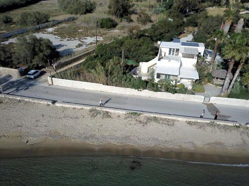 two people walking down a road next to the water at Ricardo by the sea in Parikia