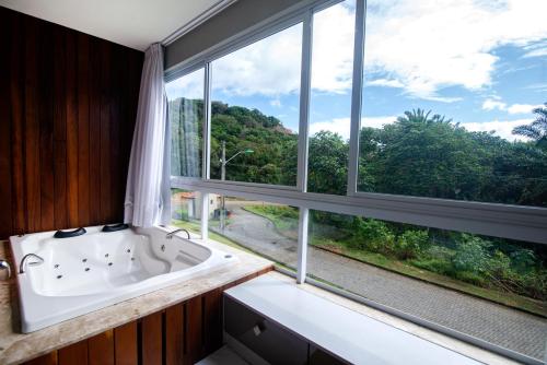 een badkamer met een bad en een groot raam bij Casasparaisomorro - Apartamento com hidromassagem in Morro de São Paulo