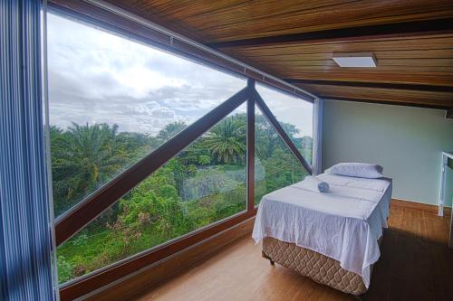 een slaapkamer met een bed en een groot raam bij Casasparaisomorro - Apartamento com hidromassagem in Morro de São Paulo