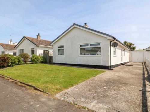 una casa blanca con un patio de césped en Jacuma, en Rhosneigr