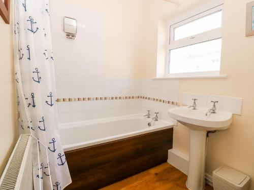 un baño con bañera y lavabo en Jacuma, en Rhosneigr