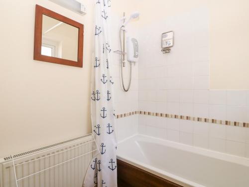 a bathroom with a bath tub and a shower curtain at Jacuma in Rhosneigr