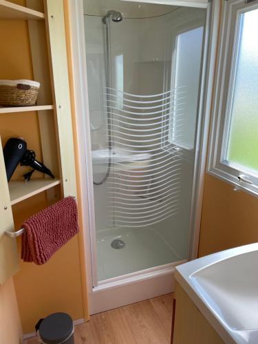 La salle de bains est pourvue d'une douche en verre et d'un lavabo. dans l'établissement Mobil-Home VUE sur MER, à Le Portel