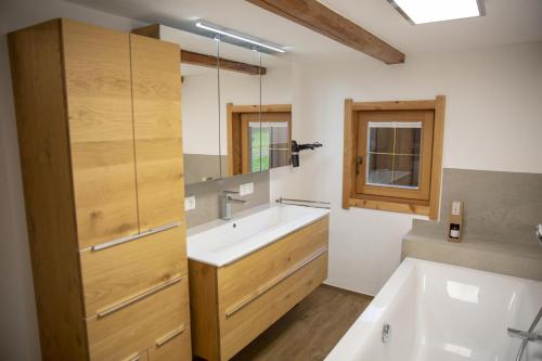 a bathroom with a sink and a tub and a mirror at Ferienwohnung Kast'l in Alpbach