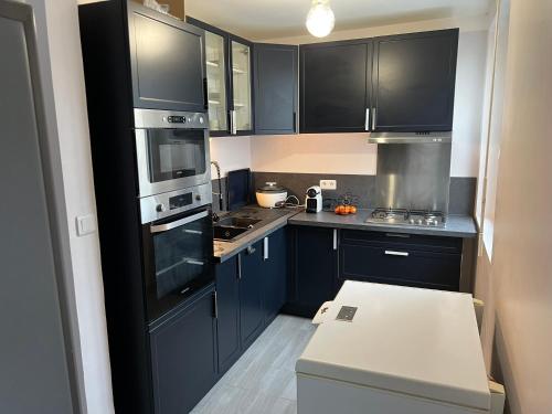 a kitchen with black cabinets and a stove top oven at Appartement près de La défense in Nanterre