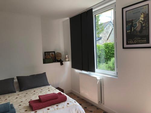 a bedroom with a bed with red pillows and a window at LA FERME DE RUSSÉ in Allonnes