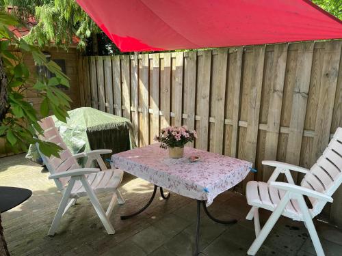 una mesa con 2 sillas y una sombrilla roja en el patio en Historische gelegen appartement more Days, en Dedemsvaart
