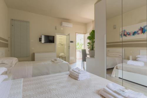 a white room with two beds and a mirror at Center Rooms in Piacenza