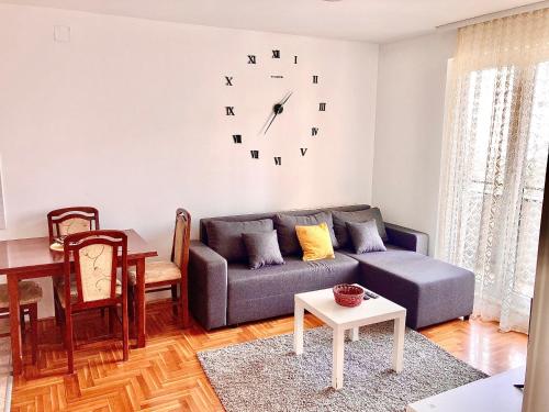a living room with a couch and a clock on the wall at Apartman 4-you 4 in Mirijevo