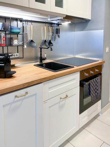 a kitchen with white cabinets and a sink at swissme - modernes Studio mit Balkon & Parkplatz & Netflix in St. Moritz