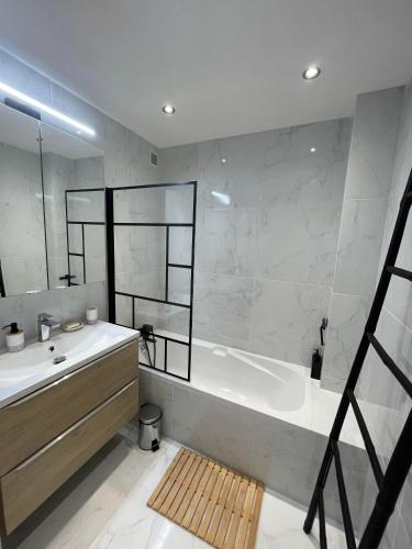 une salle de bain avec une baignoire et un lavabo dans l'établissement Comfortable apartment with parking - Antibes Riviera, à Antibes