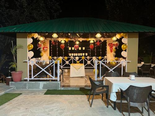 Resorts By The Baagh, Bhimtal في بهيمتال: شرفة عليها طاولات وكراسي
