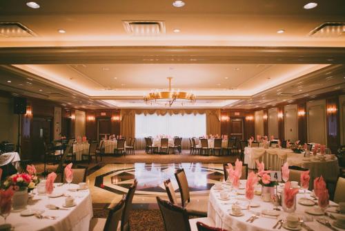 a banquet hall with white tables and chairs and a chandelier at Norwalk Inn & Conference Center in Norwalk