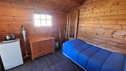 ein Schlafzimmer mit einem blauen Bett in einer Holzhütte in der Unterkunft Knuffiges Ferienhaus Sternchen in Zinnowitz