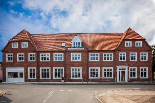 a large red brick building with white windows at Skovsgård Hotel in Brovst