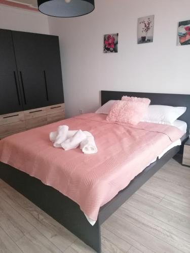 a bed with a stuffed animal on a pink blanket at Garsoniera P2 in Craiova