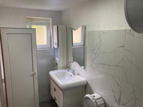 La salle de bains blanche est pourvue d'un lavabo et d'un miroir. dans l'établissement Bujtina Arturi, à Valbonë