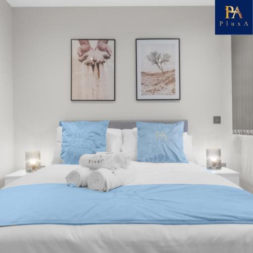 ein Schlafzimmer mit einem blauen und weißen Bett mit Handtüchern darauf in der Unterkunft Pluxa Larimar - Spacious Apt with Private Entrance, Workspace & Wi-Fi in Harrow