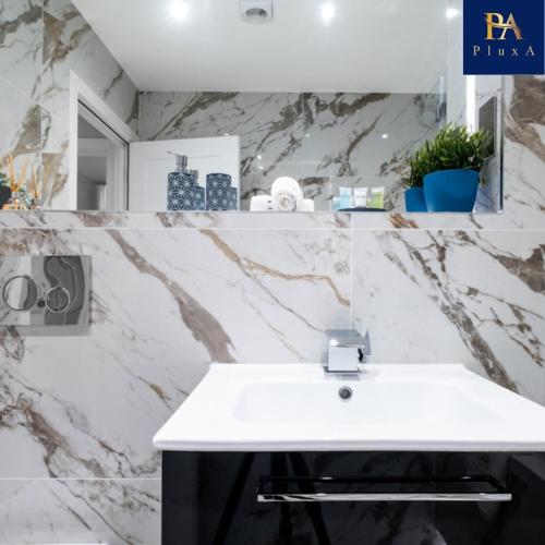 a bathroom with a white sink and a marble wall at Pluxa Larimar - Spacious Apt with Private Entrance, Workspace & Wi-Fi in Harrow