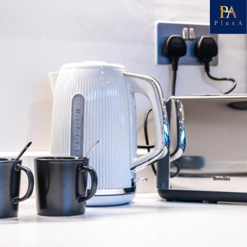a tea kettle and two cups on a counter at Pluxa Larimar - Spacious Apt with Private Entrance, Workspace & Wi-Fi in Harrow