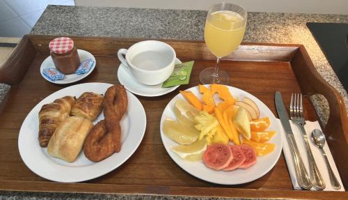 a tray with two plates of food and a glass of orange juice at Pare LODGE TAHITI in Pirae
