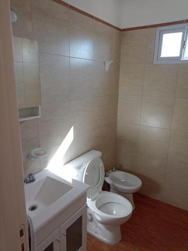 La salle de bains est pourvue de toilettes blanches et d'un lavabo. dans l'établissement Departamento en primer piso, à Venado Tuerto