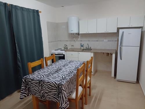 La cuisine est équipée d'une table, de chaises et d'un réfrigérateur. dans l'établissement Departamento en primer piso, à Venado Tuerto