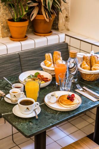 a table with plates of breakfast foods and cups of coffee at Hôtel Mathis Elysées in Paris