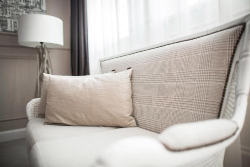a white chair with a pillow and a lamp at Hotel Wodnik in Wrocław