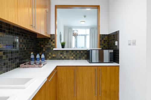 a kitchen with a sink and a microwave at Vacay Lettings - 1 Bed at Iris Blue, Dubai Marina in Dubai