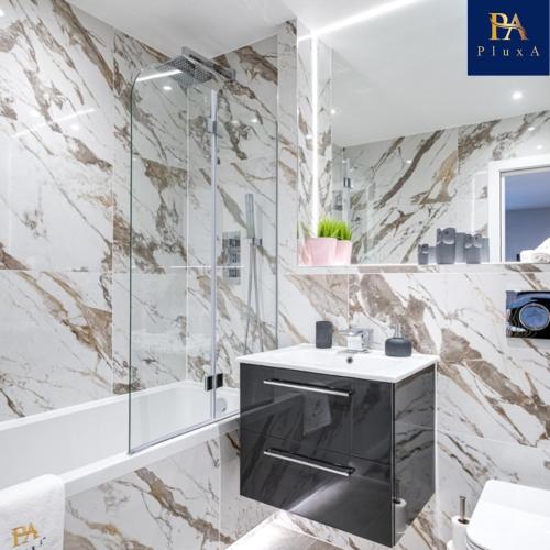 a bathroom with a sink and a glass shower at Pluxa Blush - Blush Gem with Private Entrance, Workplace, Harrow Haven in Harrow