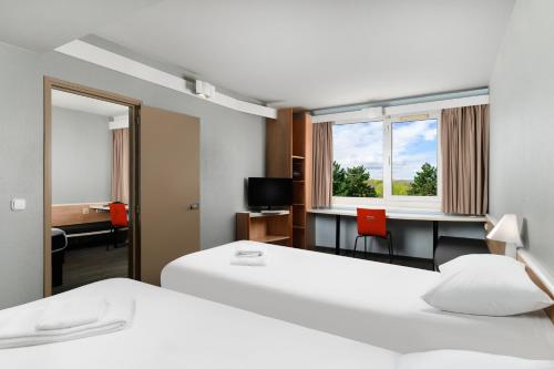 una camera d'albergo con 2 letti, una scrivania e uno specchio di Ibis Budapest Citysouth a Budapest