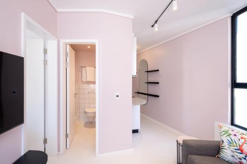 Cape Town的住宿－The Flamingo Private Apartments by Perch Stays，一间拥有白色墙壁的客房,设有通往浴室的楼梯