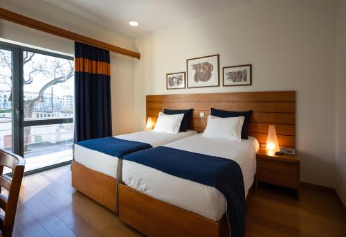 sypialnia z dużym łóżkiem i dużym oknem w obiekcie Hotel Pombalense w mieście Pombal
