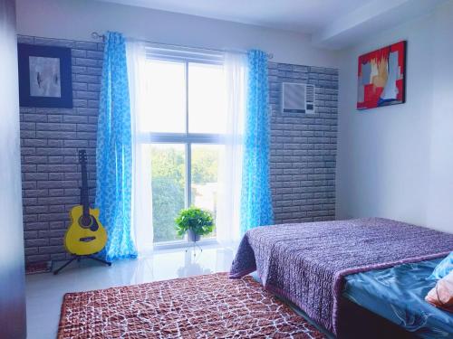 a bedroom with a bed and a window with a guitar at Arthomes BB6 in Mandaue City