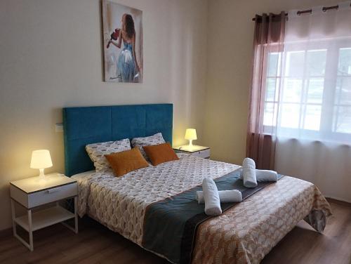 Schlafzimmer mit einem Bett mit blauem Kopfteil und einem Fenster in der Unterkunft CASA DA DUNA - Salir do Porto in Salir de Porto