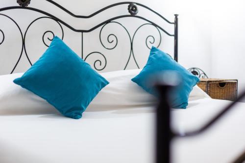 Una cama blanca con dos almohadas azules encima. en Aetòs Home, Porto Pino hill, en Porto Pino
