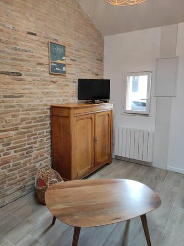 - un salon avec une table en bois et une télévision dans l'établissement Studio de charme indépendant, à Belin-Beliet