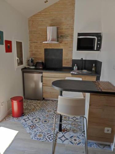 kuchnia ze stołem, krzesłami i kuchenką mikrofalową w obiekcie Studio de charme indépendant w mieście Belin-Beliet