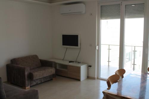 a living room with a couch and a tv and a chair at Blue Apartments & Hotel Shengjin in Shëngjin