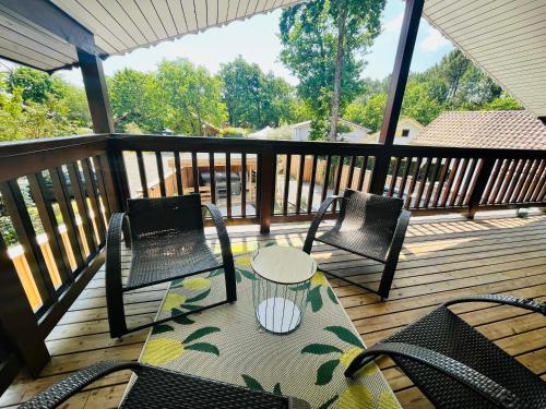 deux chaises et une table sur une terrasse en bois dans l'établissement Chalet domaine forge 6-8pers jacuzzi terrasse plancha proche commerces, à La Teste-de-Buch
