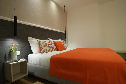 a bedroom with a bed with an orange blanket and pillows at Enea Suite in Trapani