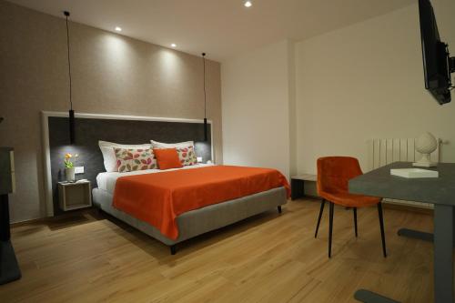 a bedroom with a bed with orange sheets and a desk at Enea Suite in Trapani