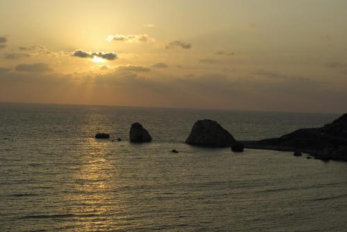 a sunset over the ocean with rocks in the water at Fantastic Junior Villa CZ02 Salamis with Gorgeous Views, Aphrodite Hills in Kouklia