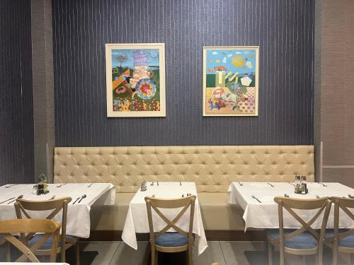 a dining room with two tables and chairs and paintings at Hotel Sato Conference & SPA Resort in Sutomore