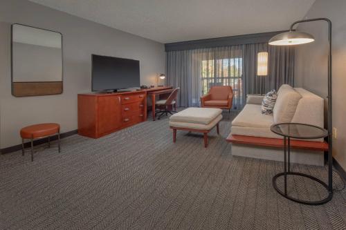 a hotel room with a bed and a desk with a television at Courtyard by Marriott Frederick in Frederick